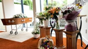 A funeral scene with casket and flowers.