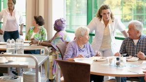 A group of senior people having lunch together in a retirement home, LTC Properties operates senior housing and living facilities