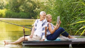 retirement stocks an older couple sitting on a dock and looking at a pamphlet