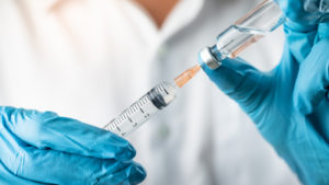 Hands of medical professional holding a syringe, symbolizing VCNX stock.