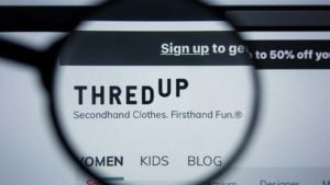 A magnifying glass zooms in on the website for ThredUp (TDUP).