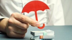 Red umbrella covering stacks of bills