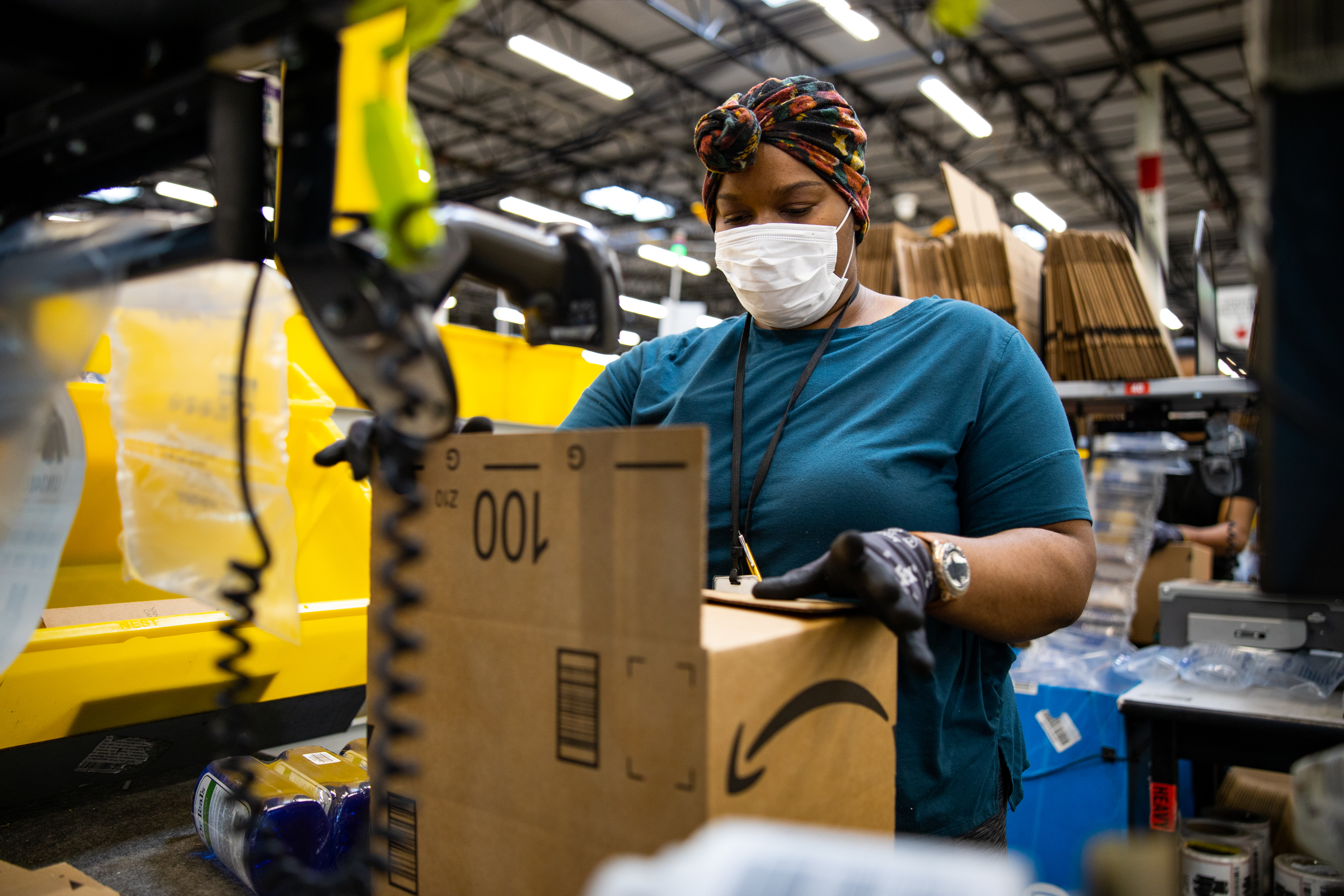 A warehouse worker packing an Amazon box.