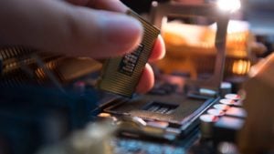 A zoomed in image of a hand placing a CPU chip onto a CPU socket.