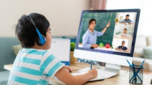 a child takes notes while attending an online class. represents education stocks. edtech stocks