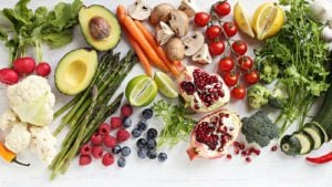 Vegetables and fruits are scattered over a white background.