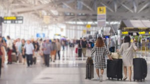 two women carrying luggage in an airport