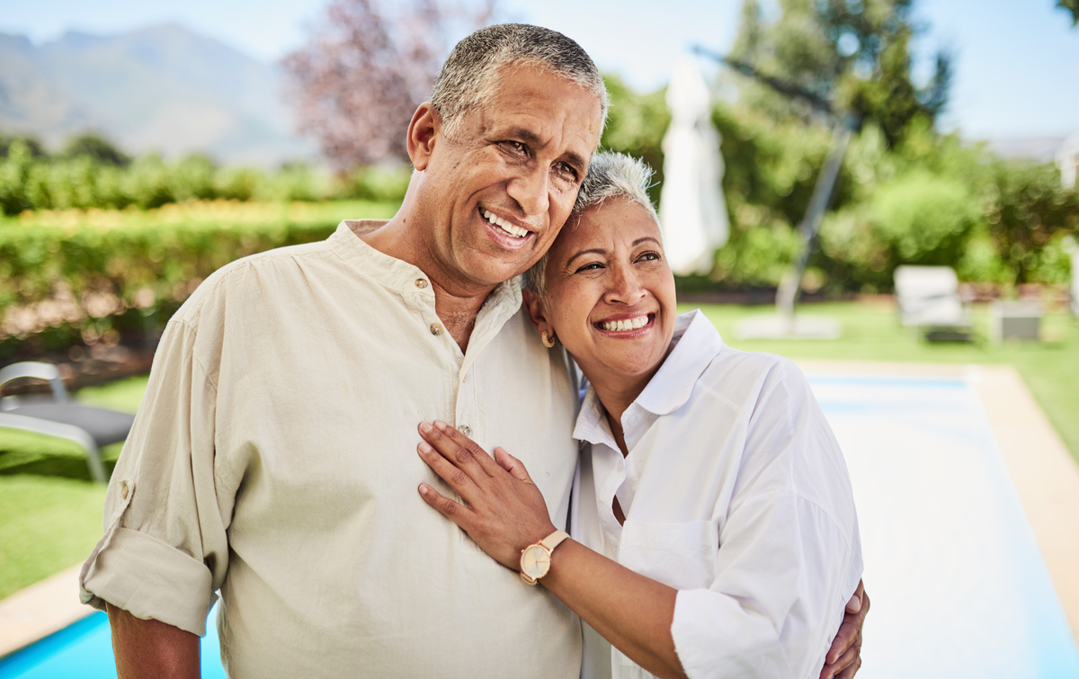 A couple smiling in front of a pool.