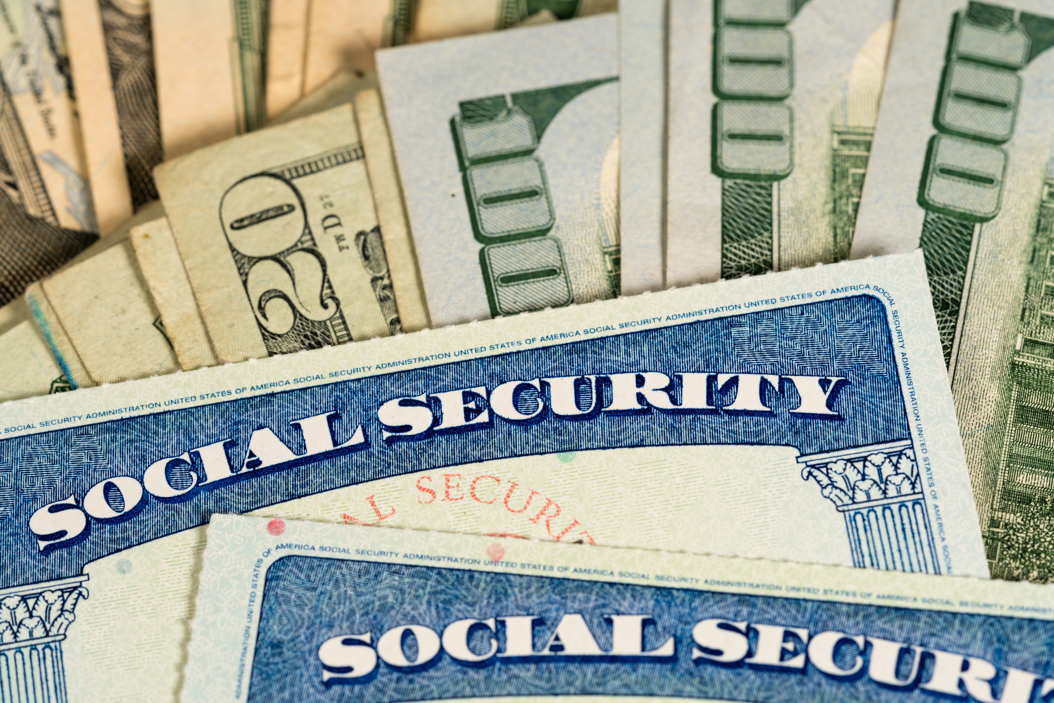 Two Social Security cards sitting on top of a pile of cash.