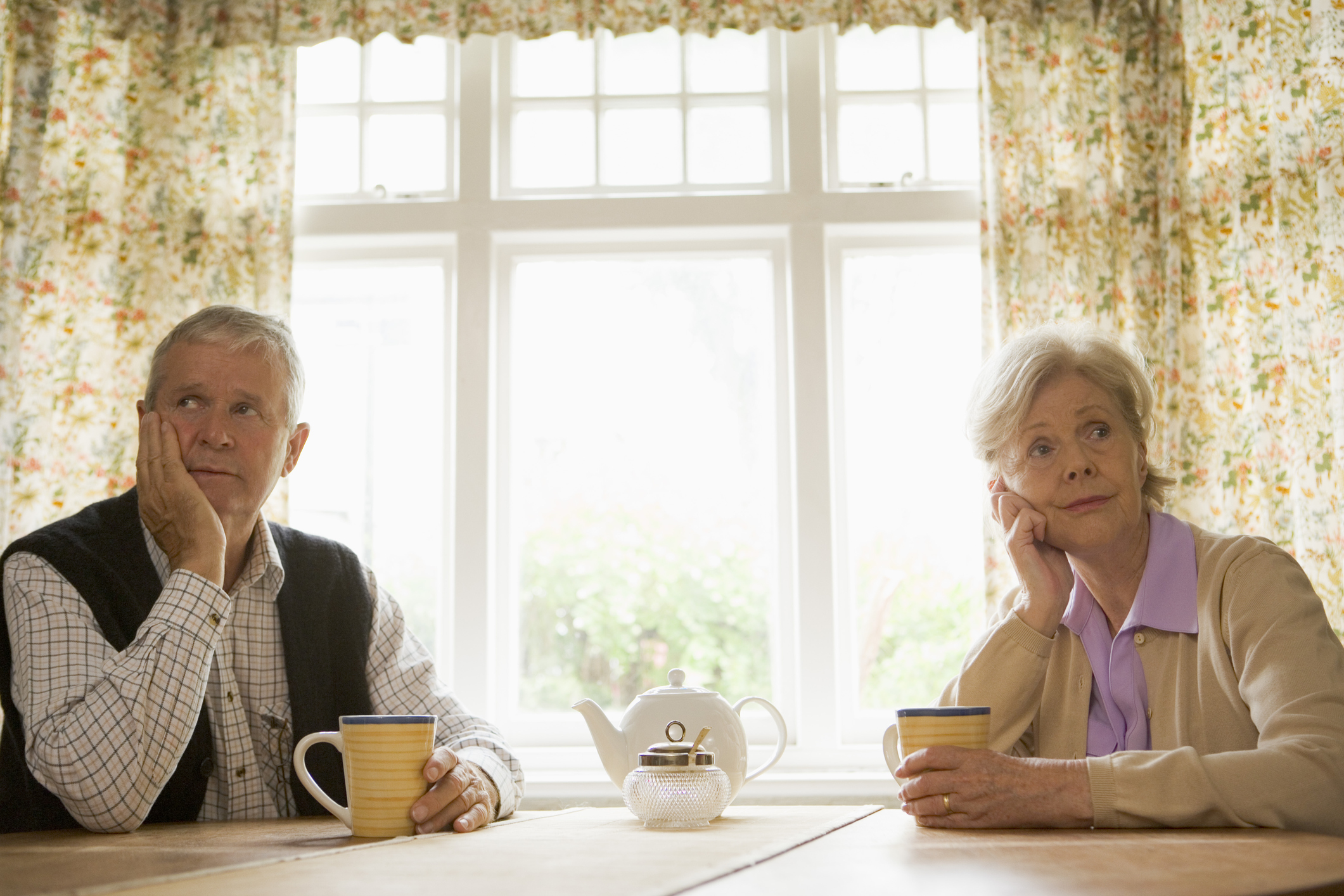 Two people at a table holding mugs.