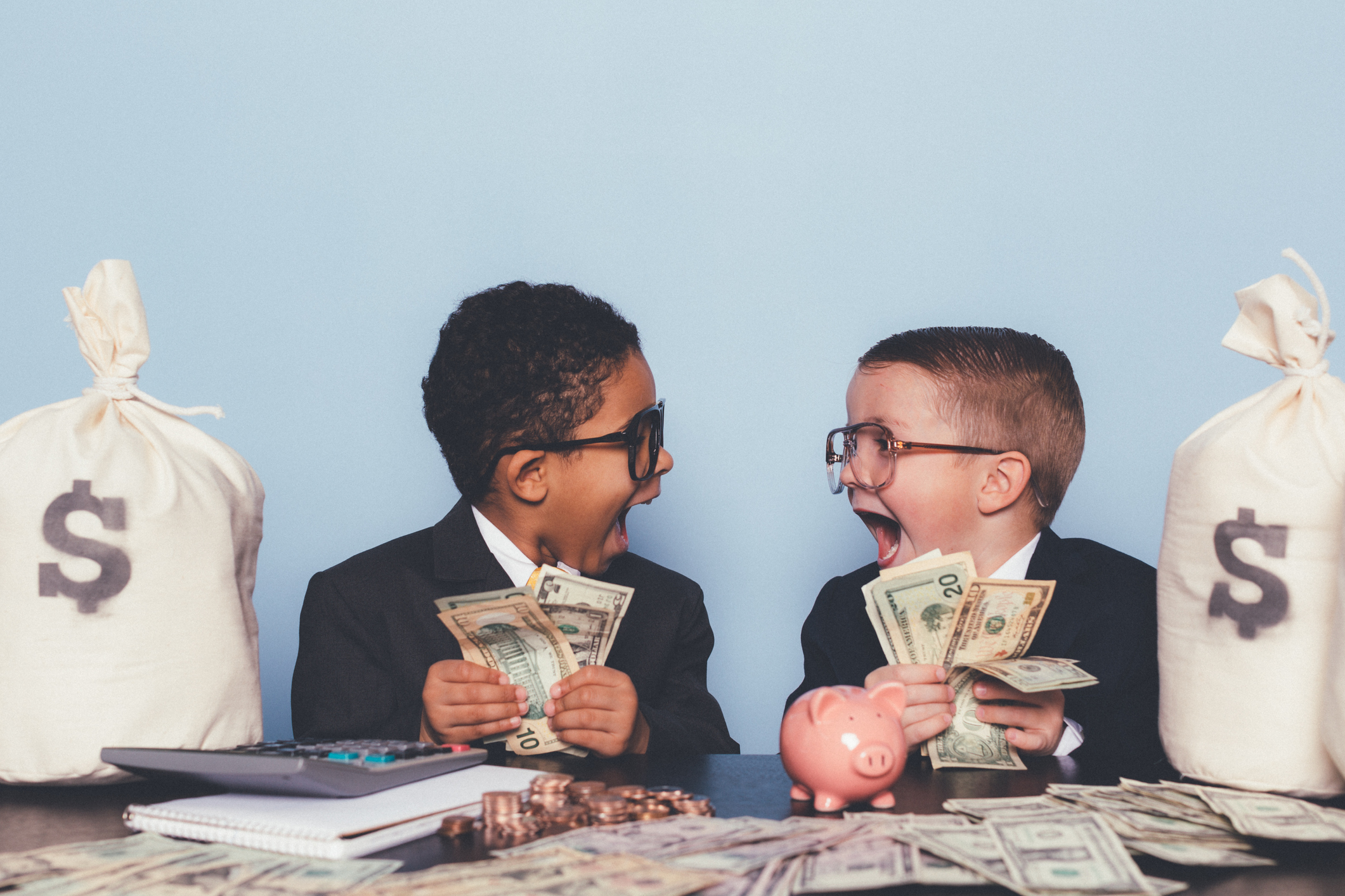 Two kids are holding lots of money and looking totally surprised by their sudden wealth. 