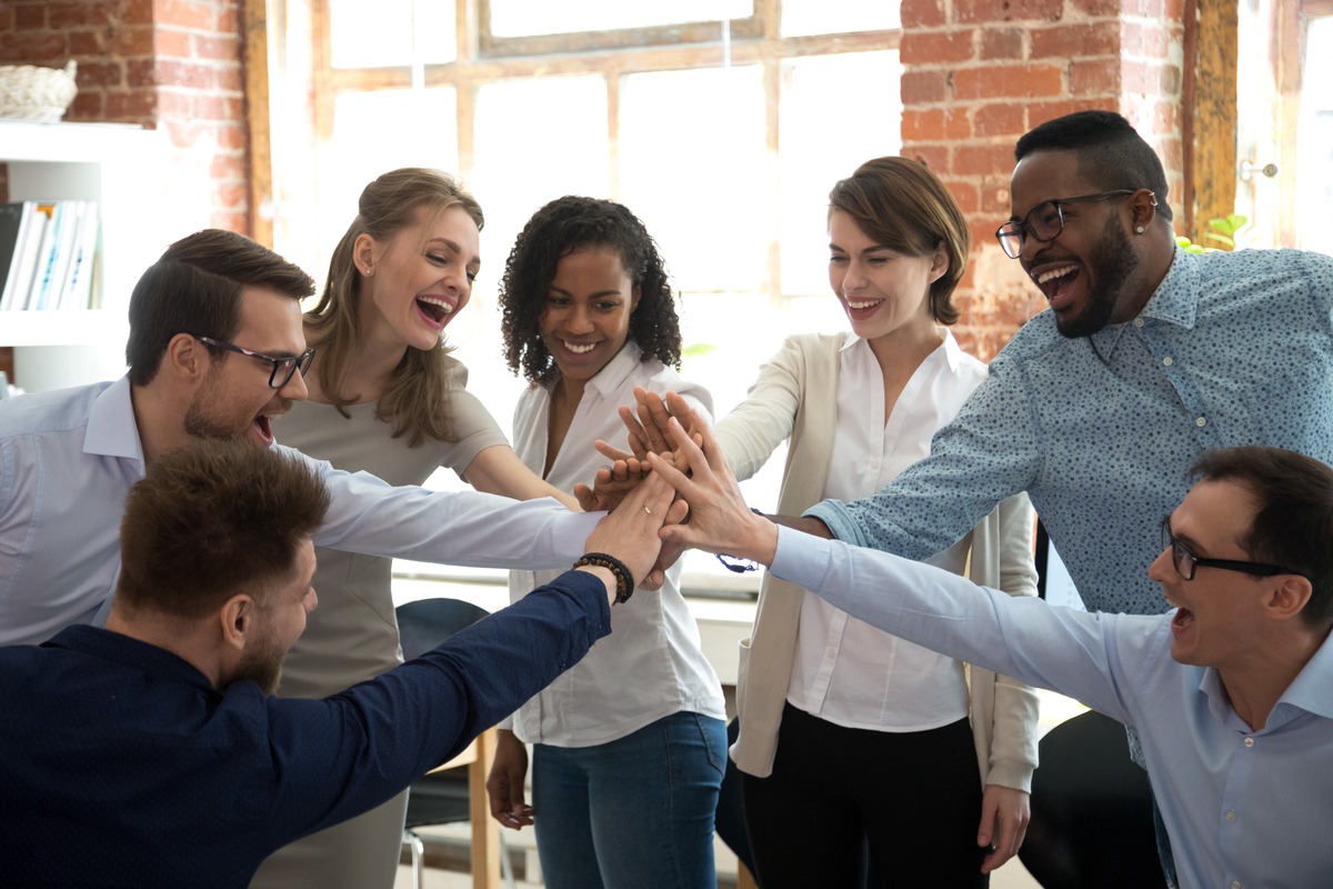 A team of happy workers standing in a circle and touching hands in the middle in an office.