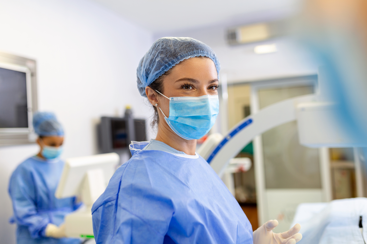 A person wearing scrubs and a face mask in a hospital.