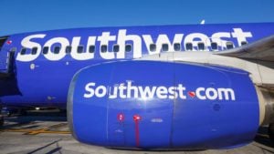 An image of the side of a blue Southwest plane with a blue sky in the background. LUV stock