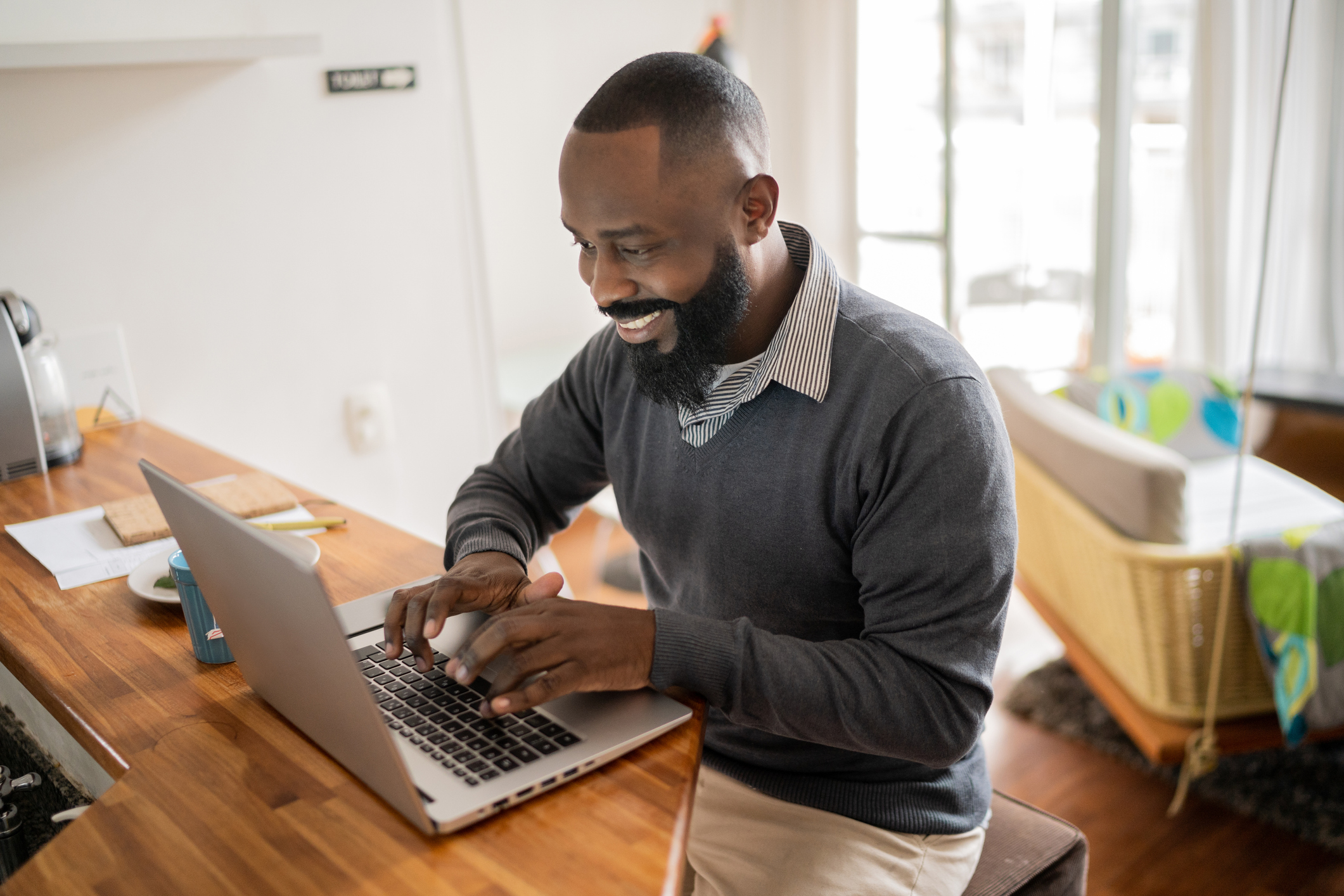 A smiling person at a laptop.