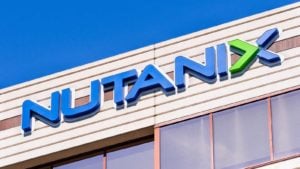 An image of a blue and green "Nutanix" logo on the front of a tan building, a row of windows below the sign, and the blue sky in the background.