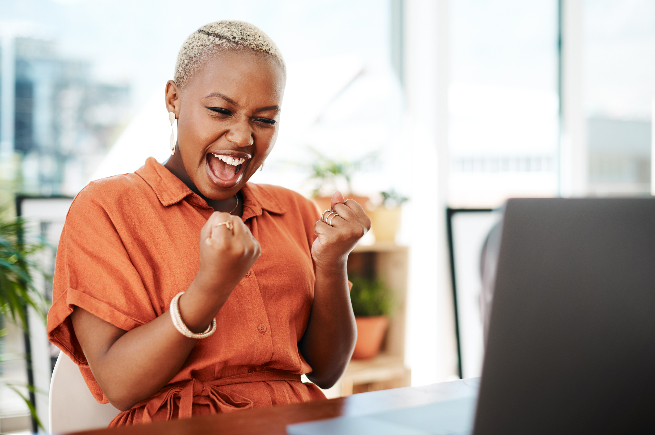 Person celebrating victory while looking at computer. 