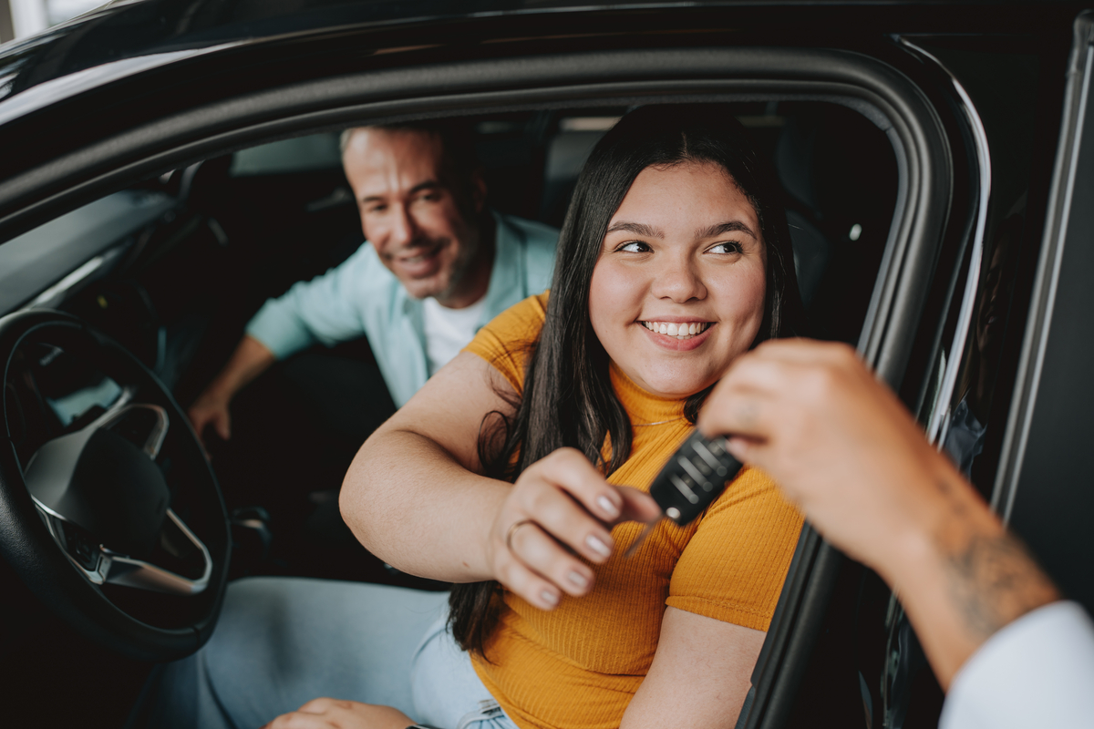 A person in a car being handed the keys to the car.