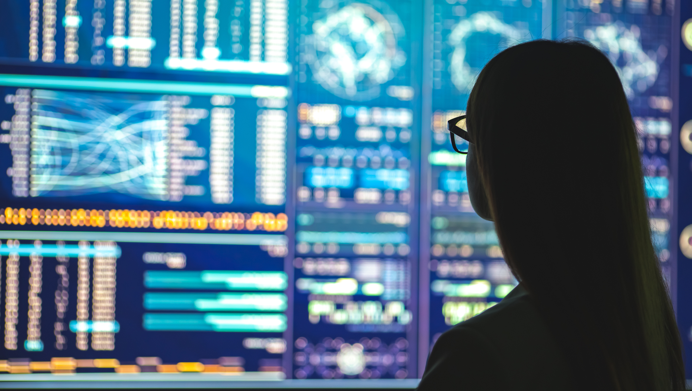 A businessperson standing near a display with various graphs.