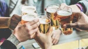 photo of peoples' hands clinking glasses of beer together in celebration