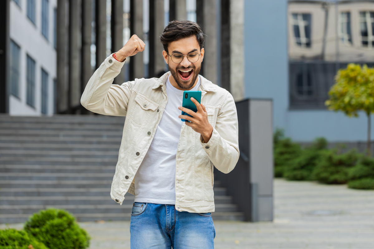 Person looking at smartphone and cheering.