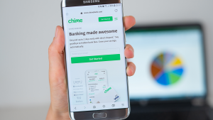 Chima app open on a phone with a blurred chart on a computer screen in background. Chima IPO.