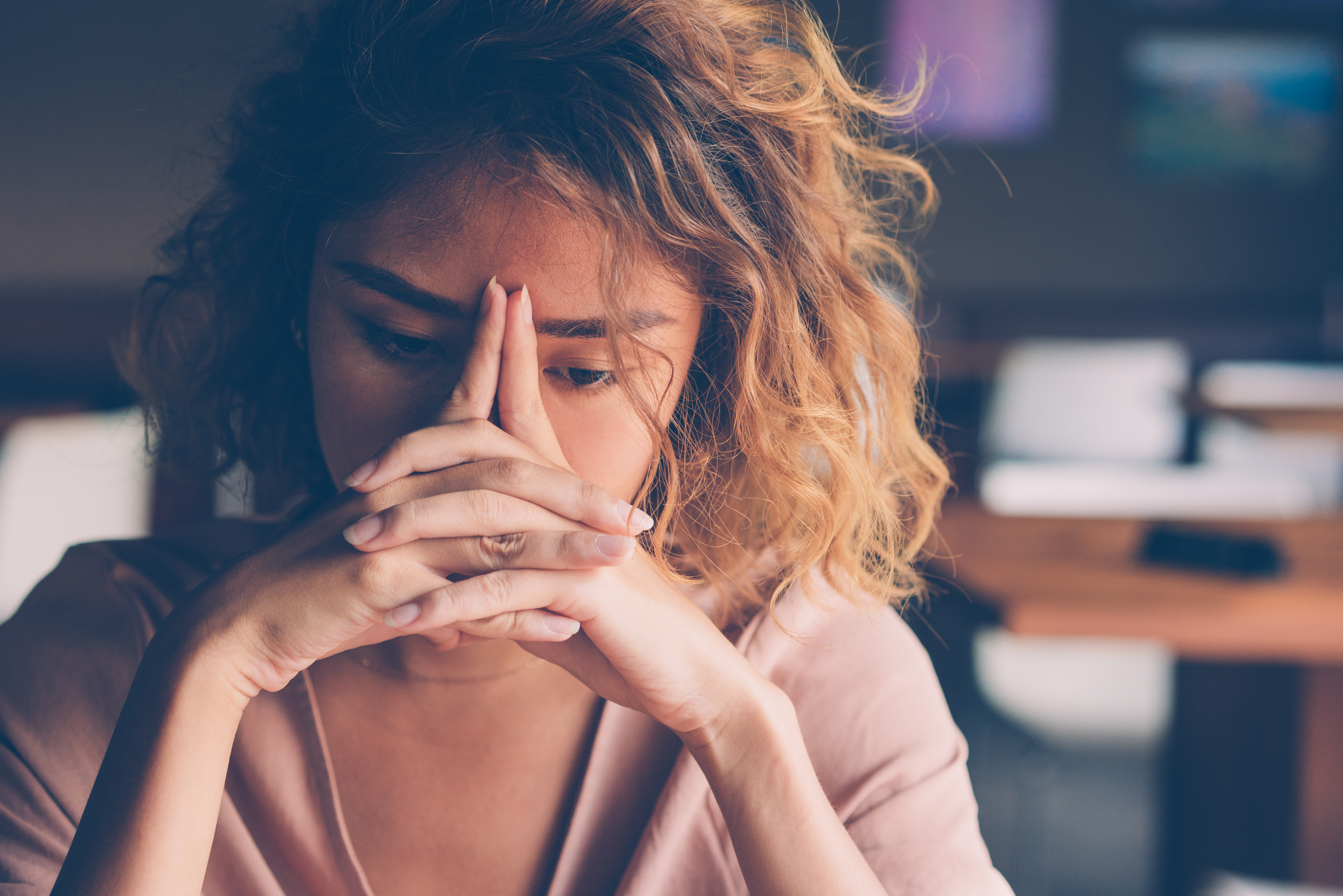 A person looks down with their hands resting on their face.