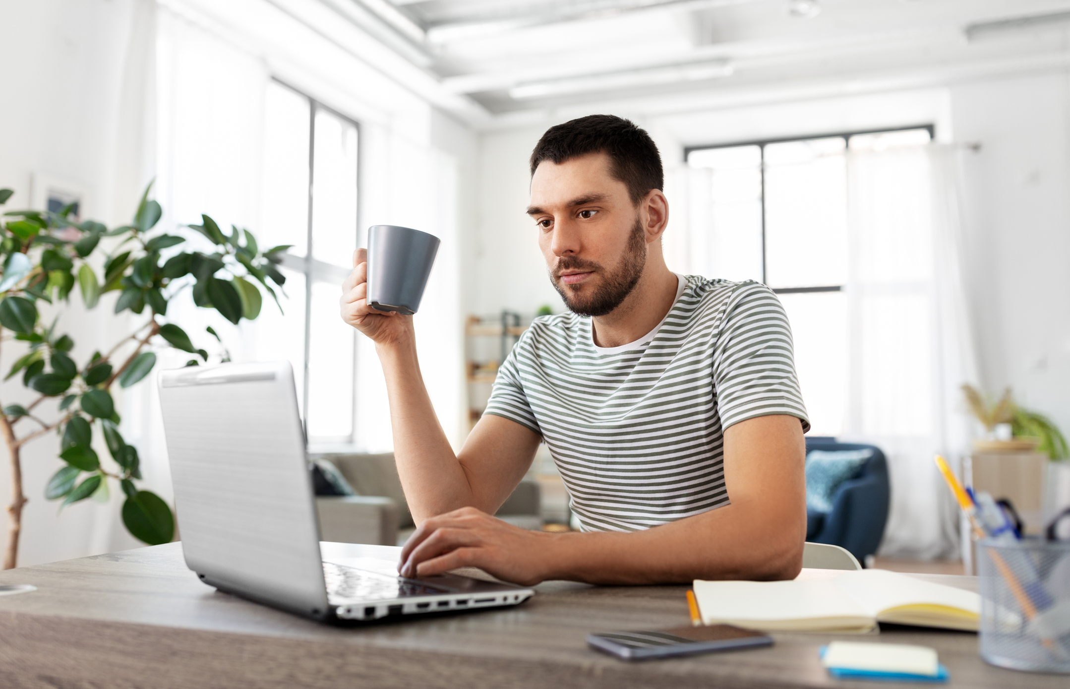 A person at a laptop holding a cup.