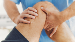 Physiotherapist doing healing treatment on patient leg. Therapist wearing blue uniform. Osteopathy, Chiropractic leg adjustment. Orthopedic therapy. ATIP stck.