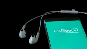 The Talkspace (TALK) logo is displayed on a smartphone screen.