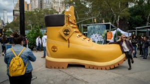 Image of a giant boot in the street surrounded by people.