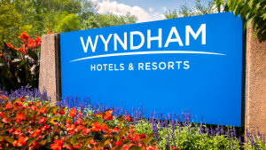 A blue sign says Wyndham Hotels & Resorts in front of red and purple flowers