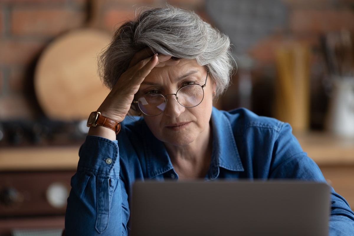 Frustrated person with hand on head looking at laptop.