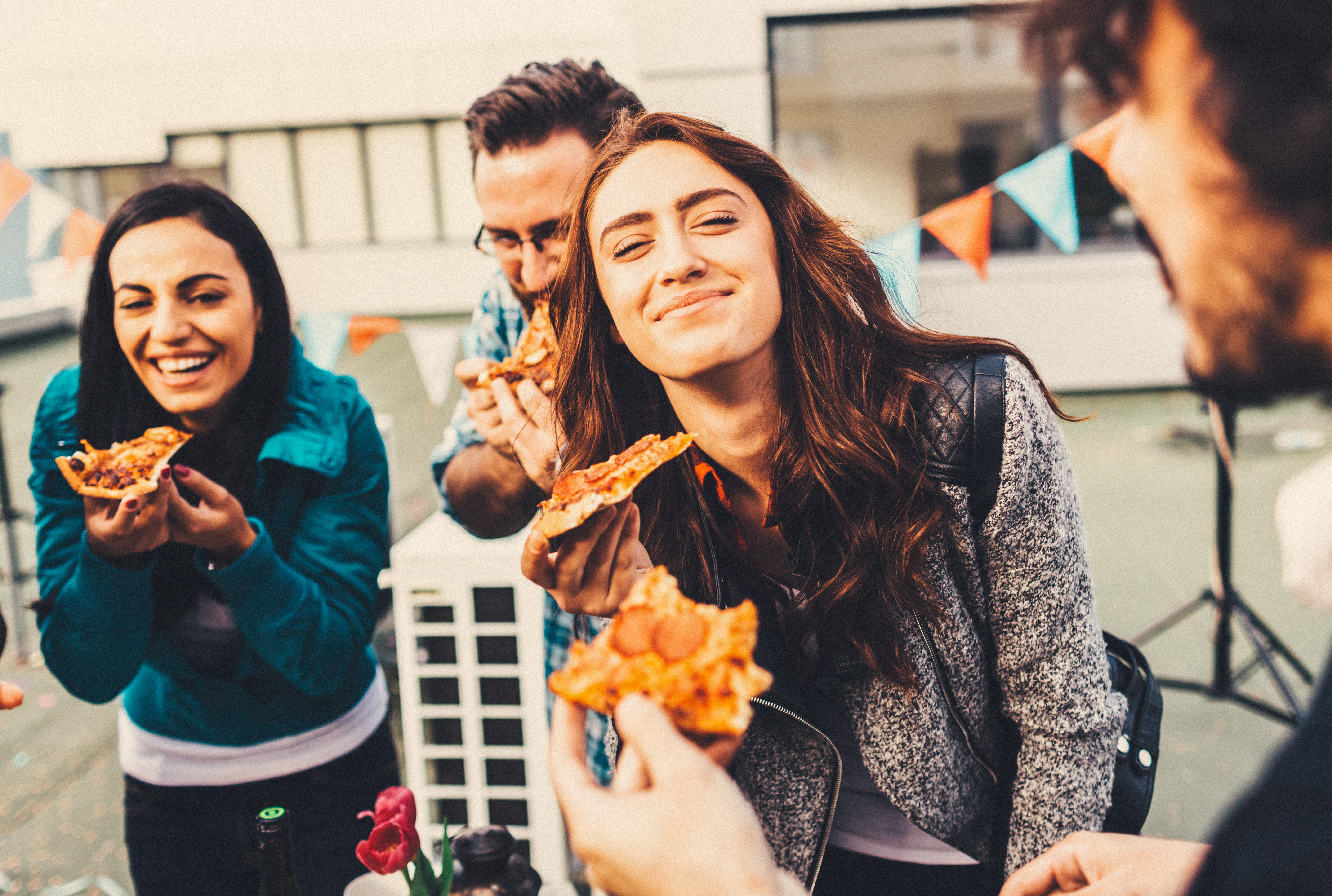 Four people smiling and eating pizza.