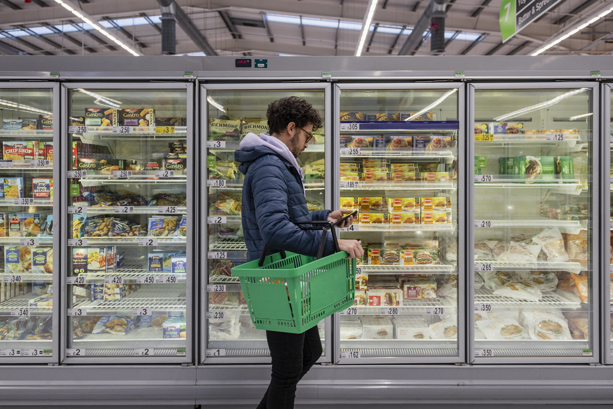 A person shopping in the freezer section of a grocery store.