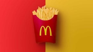 An image of a red McDonald's french fry container with the yellow "M" logo on it in front of a half red and half yellow background.