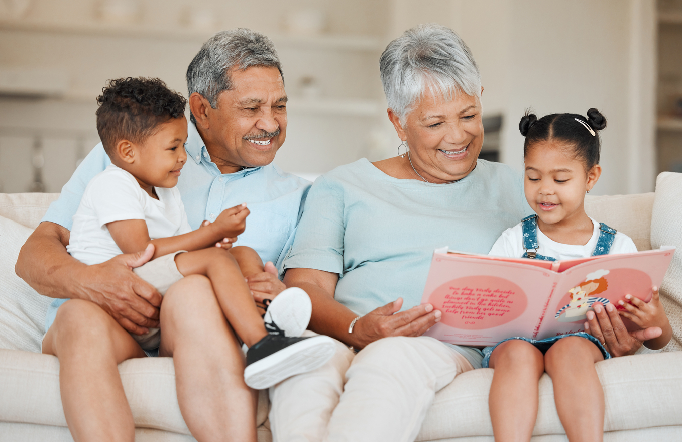 Smiling couple reading book to children.