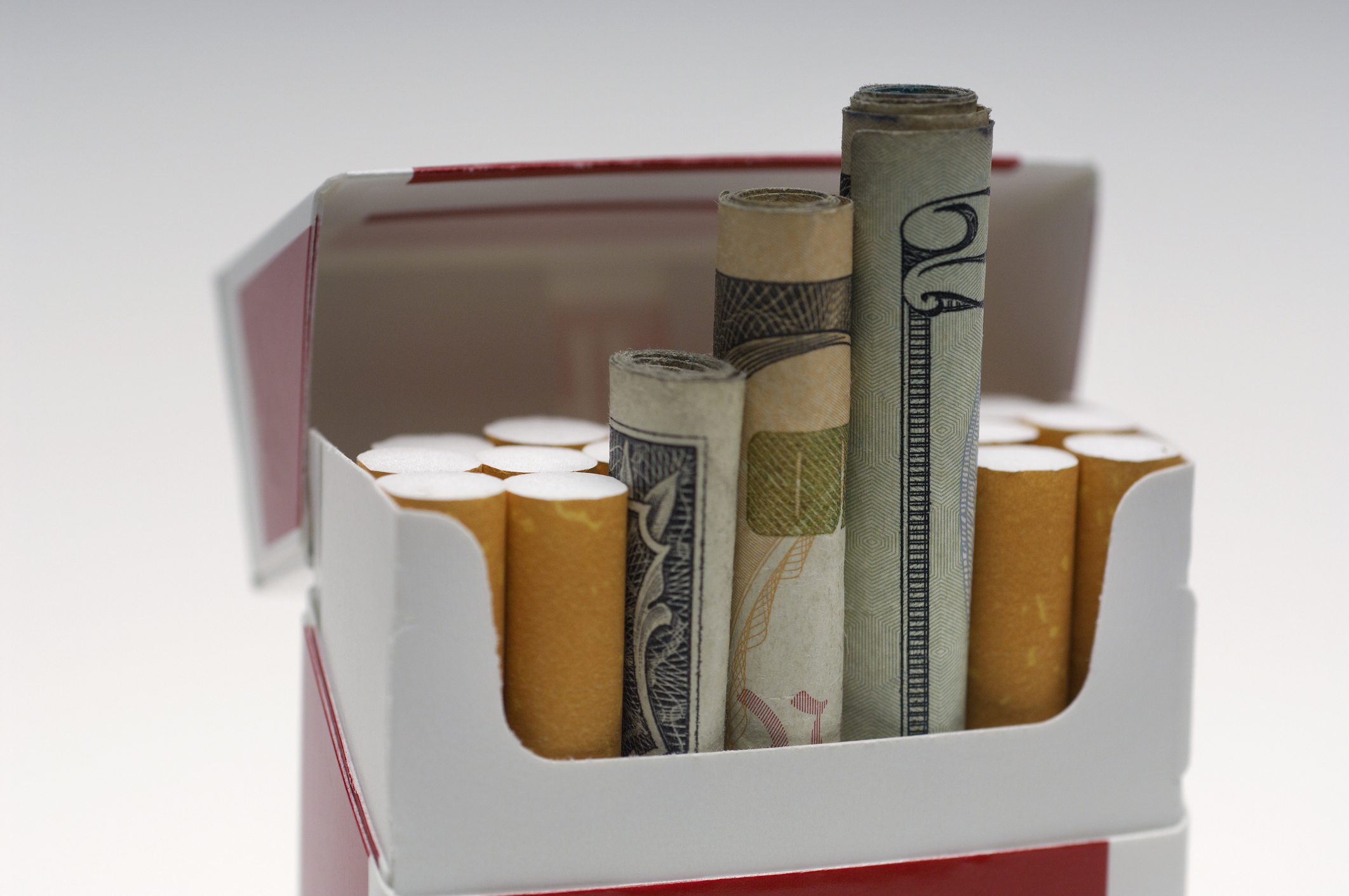 Cash rolled up inside a cigarette box alongside cigarettes.