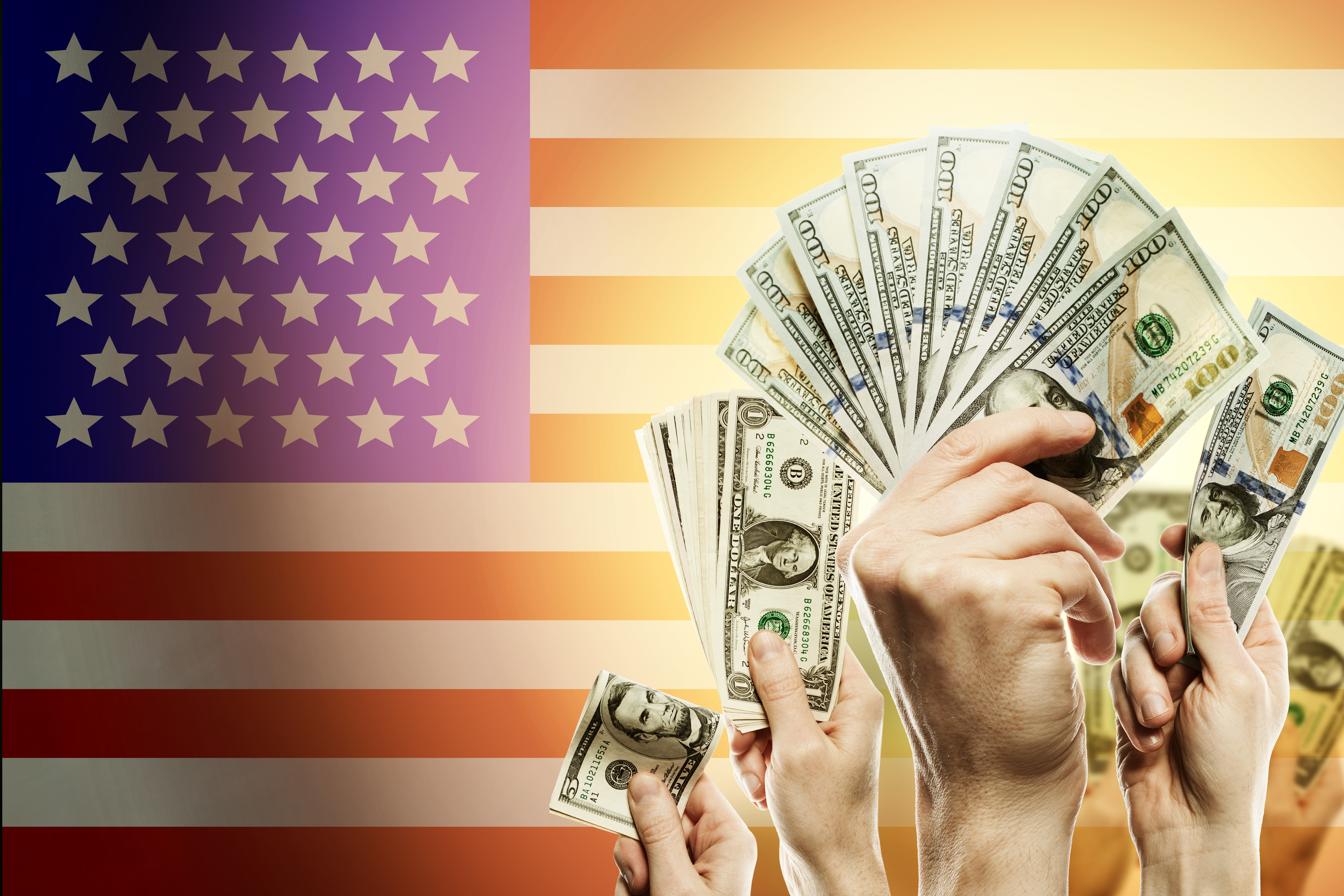 Hands holding up fans of cash in front of an American flag.