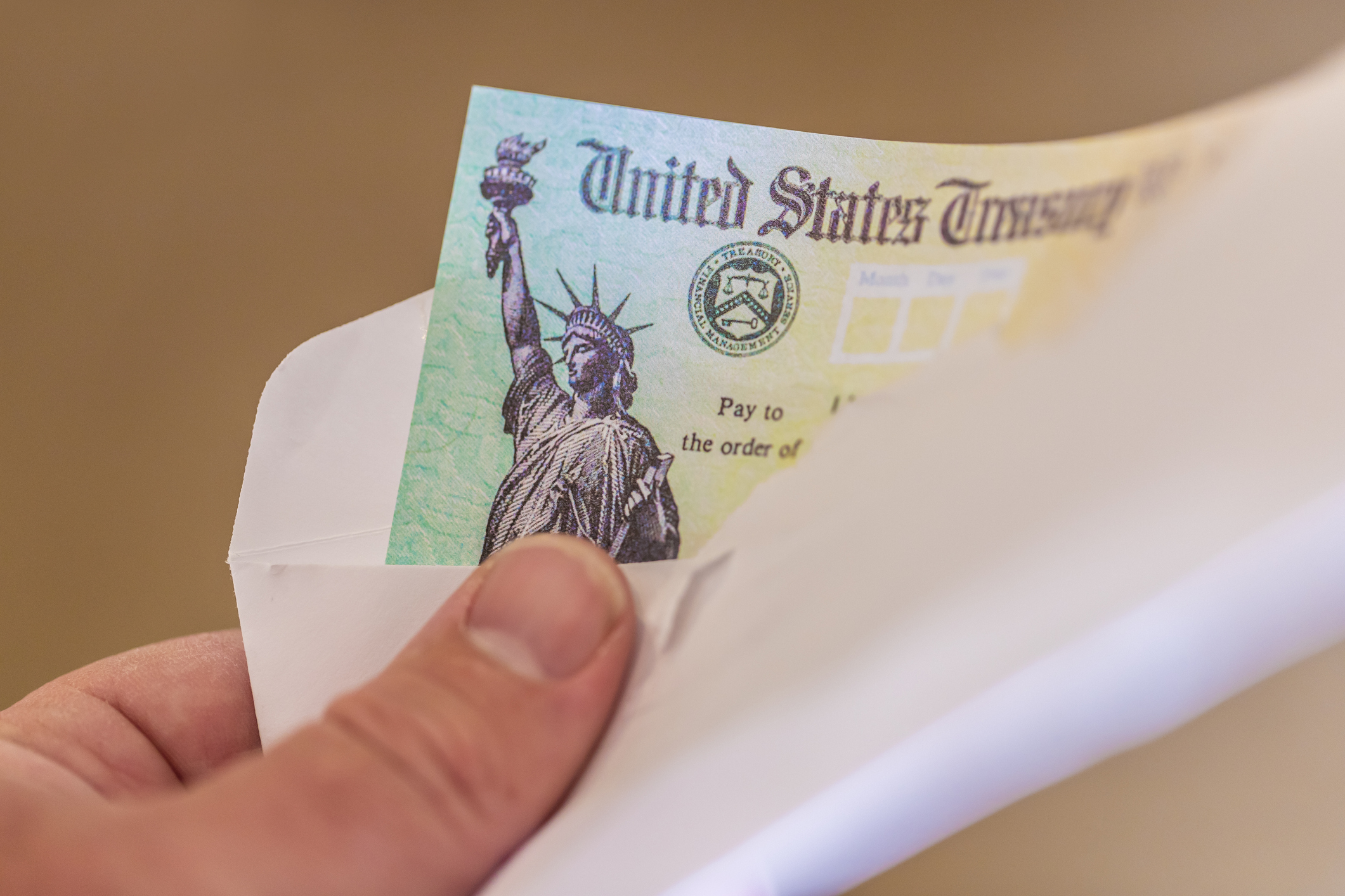 A person holding a check from the United States Treasury in an envelope.