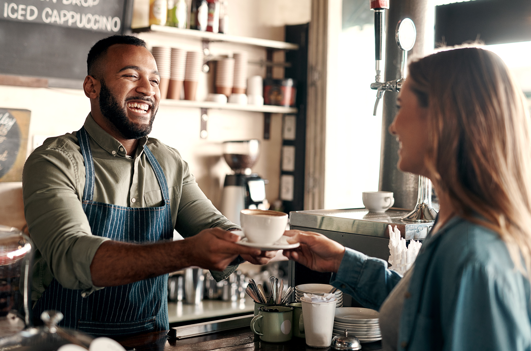 A barista serving a cup of coffee to a customer.