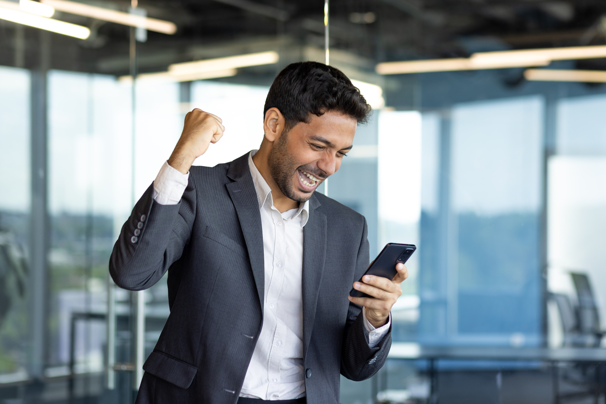 Person in business attire gesturing enthusiastically at an electronic mobile device.