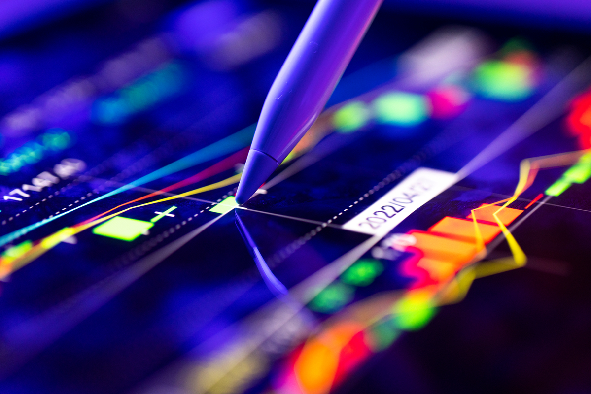 A stylus pressed on a screen showing a stock chart.