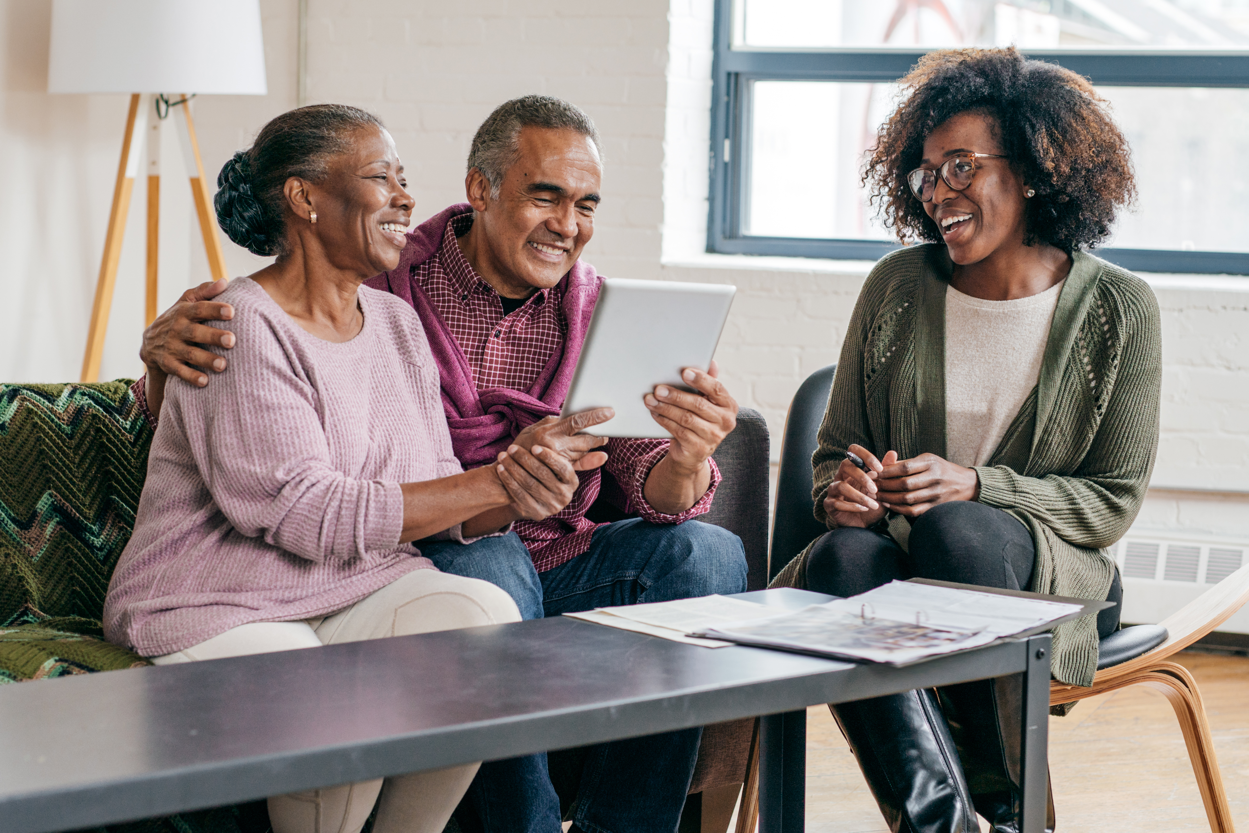 Three people looking at a tablet and smiling.