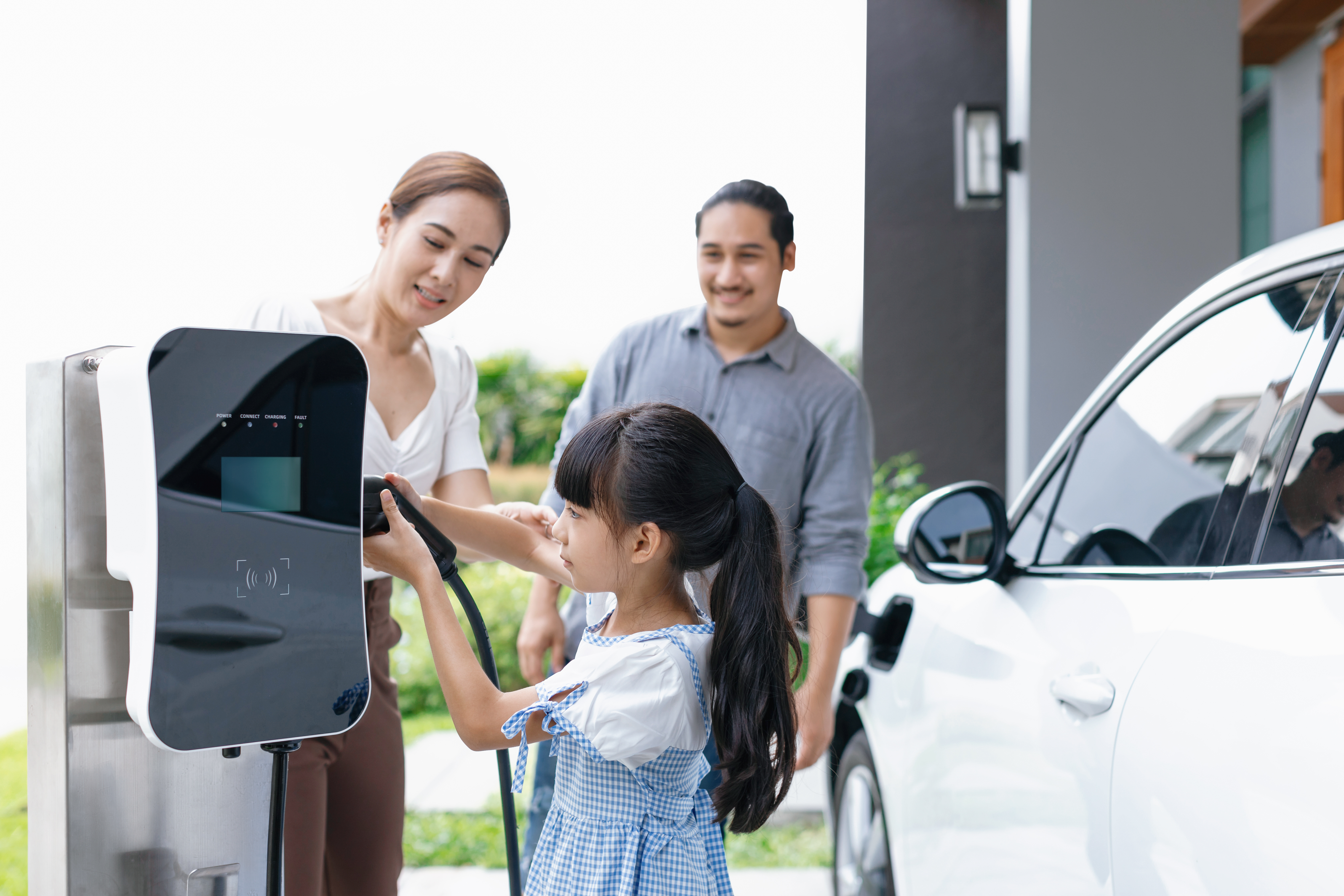 A child helps charge a family's EV at a charging station.