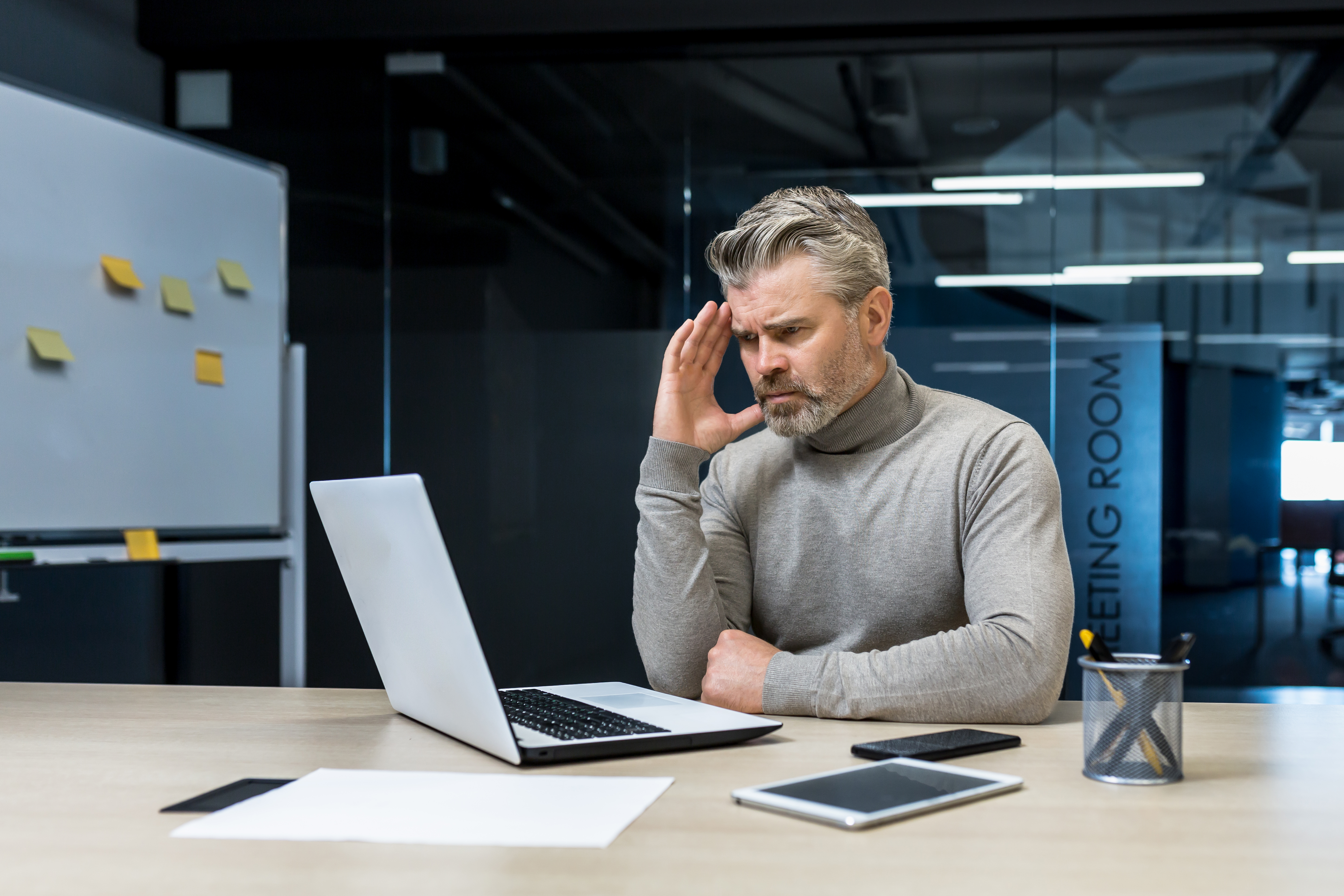 A frustrated man looking at a computer screen.