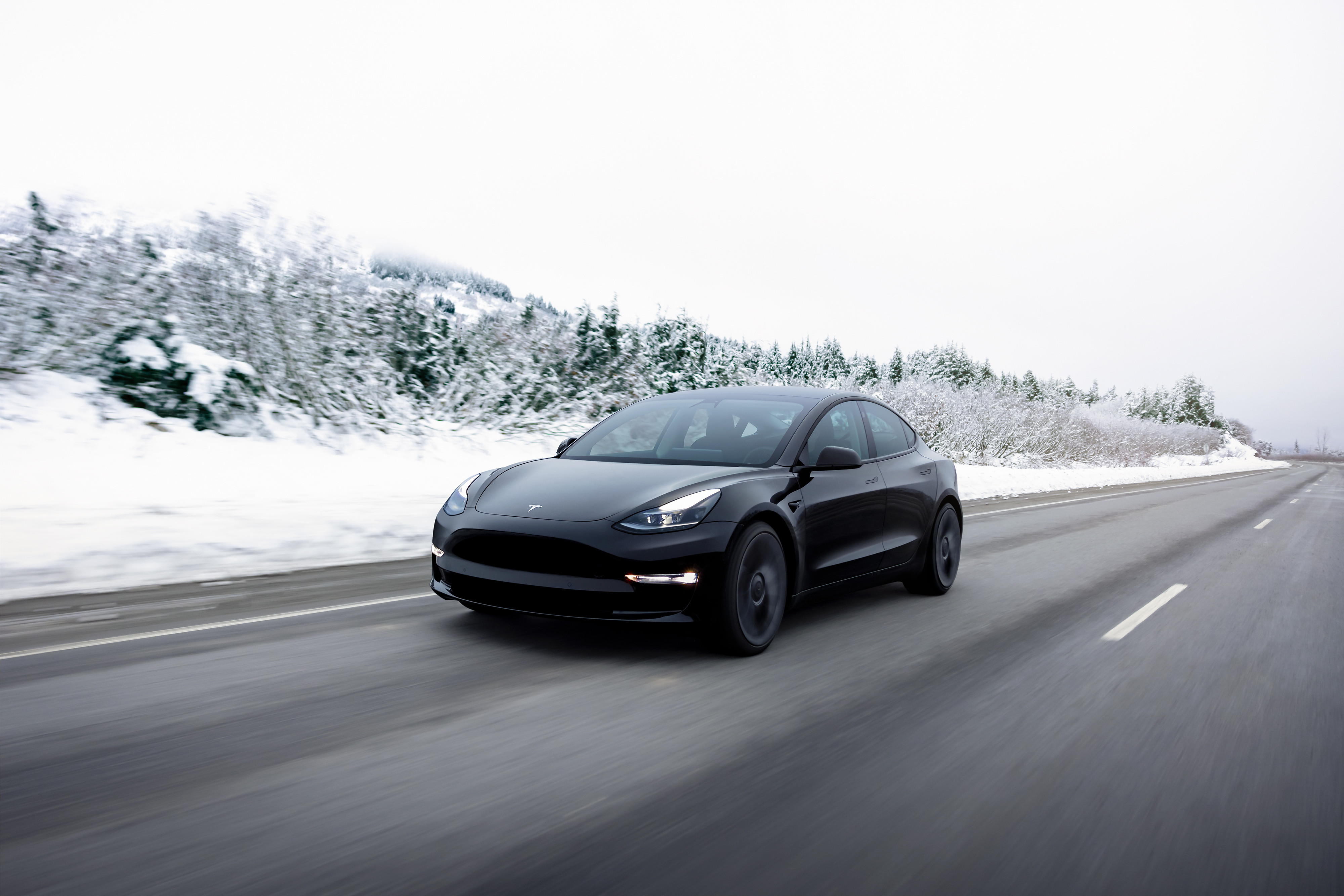 A Tesla Model 3 going down on a wintry road.