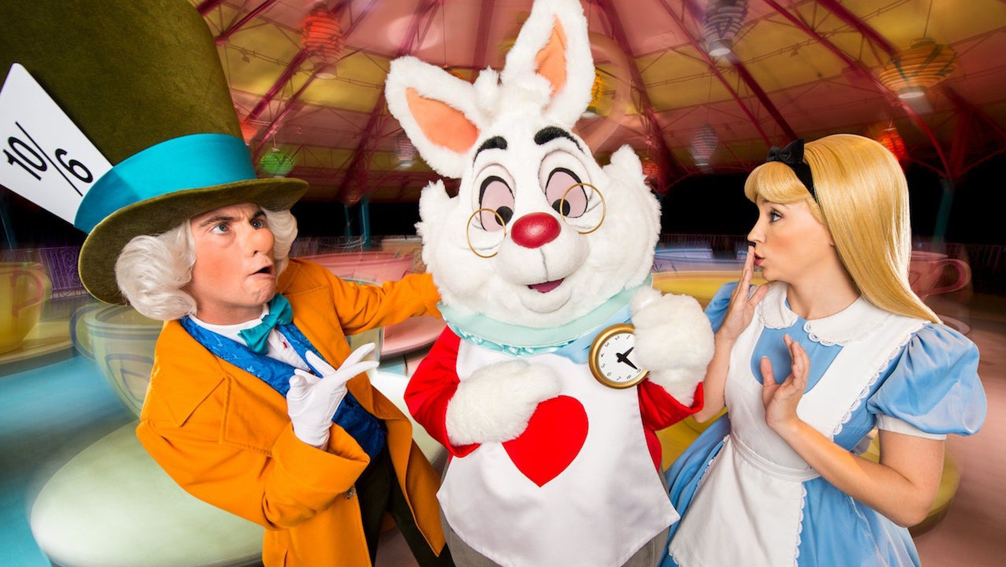 Alice in Wonderland with the Mad Hatter and Rabbit posing in front of their spinning teacup ride.