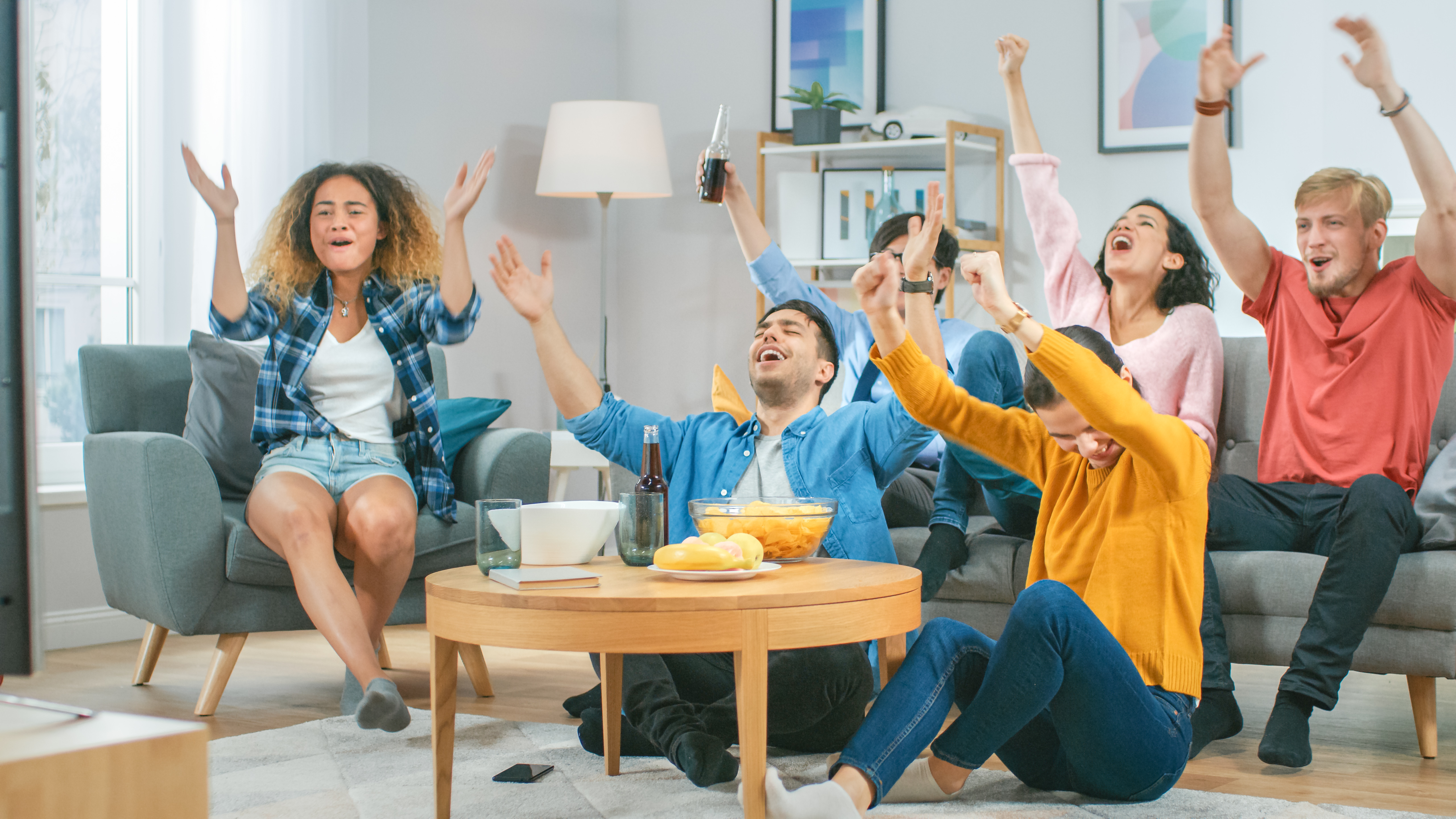 A group of friends cheering in front of a TV.