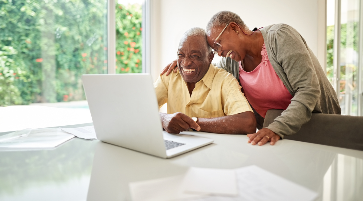 Two people sitting in front of a laptop on a table.